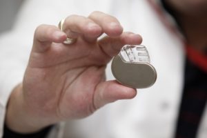 Close up of a hand holding a pacemaker device.