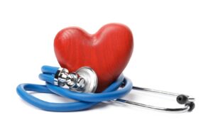 A red, wooden heart with a blue stethoscope wrapped around it.